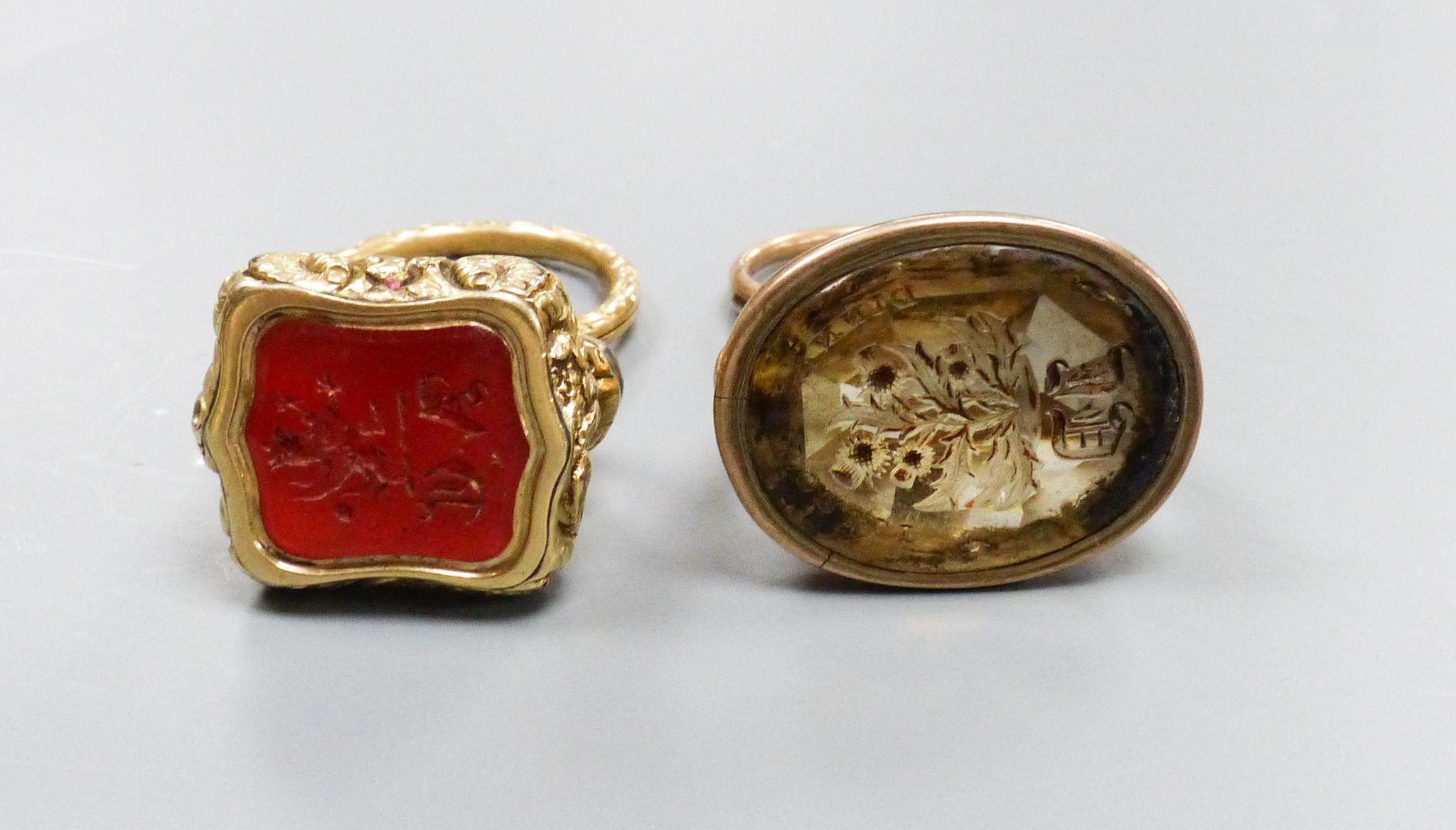 Two 19th century yellow metal overlaid fob seals, one with citrine and one with carnelian, both matrix carved with family crest, largest 30mm.